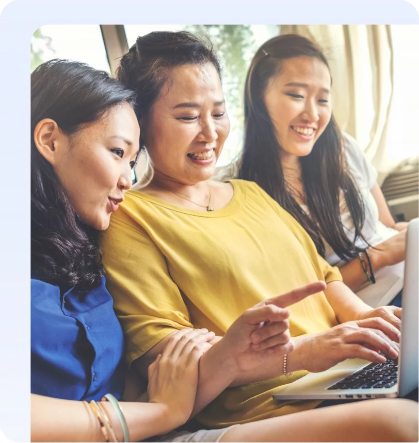 Mother and her daughters happily browsing the internet on a laptop